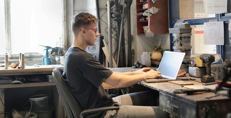 focused young man working on laptop in workshop