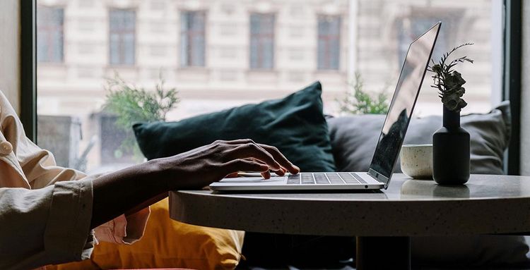 person in red pants sitting on couch using macbook