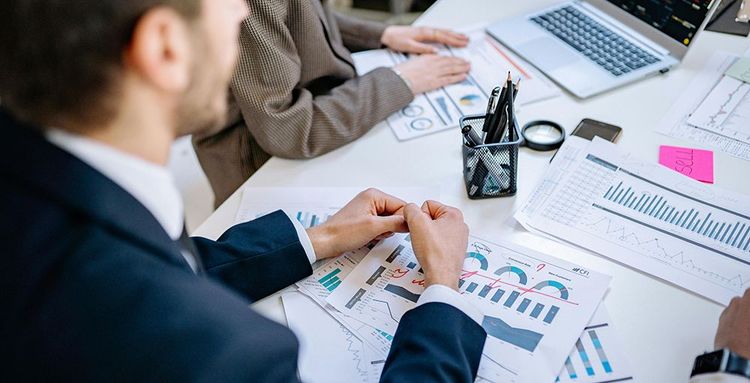 man in black suit jacket reviewing printed reports