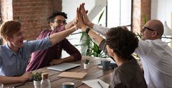 employees high-fiving during team meeting