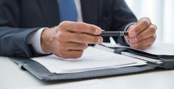 financial advisor holding a pen over documents