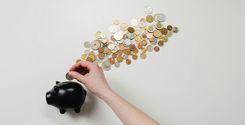 person putting coin in a piggy bank