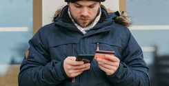 focused young man making online shopping with smartphone and credit card