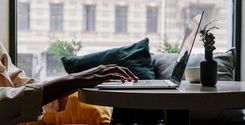 person in red pants sitting on couch using macbook