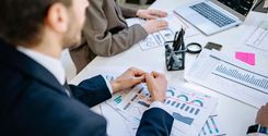 man in black suit jacket reviewing printed reports