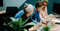 three women discussing documents at work